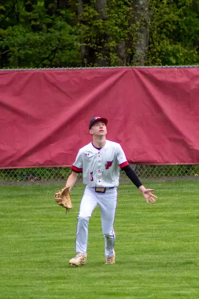 Outfielder tracking a fly ball against the fence