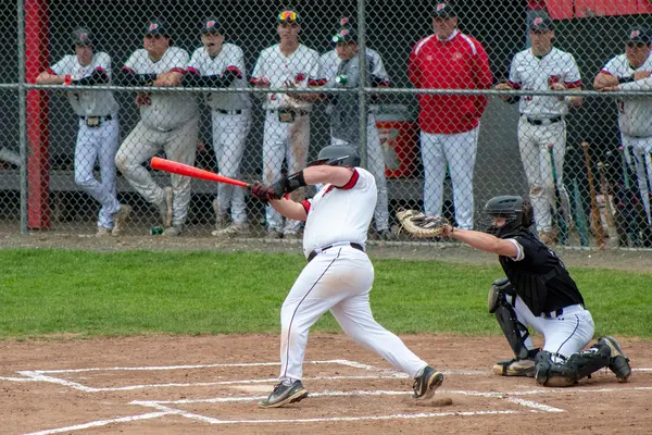 Pomperaug batter following through on a big swing as the catcher reaches for the pitch