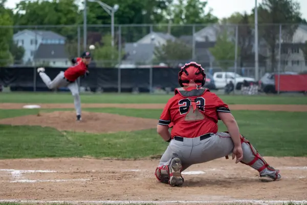 Catcher setting a target as the pitcher winds up in the background