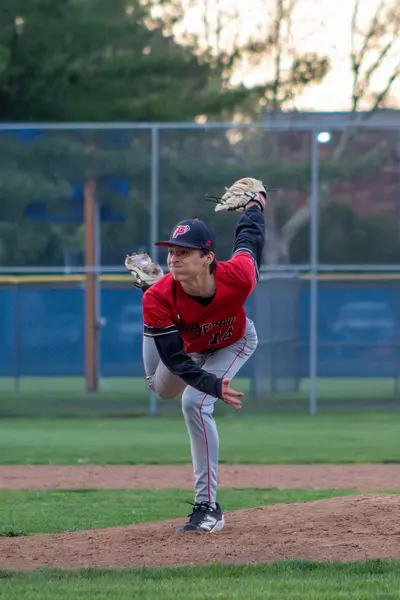 Pitcher finishing his delivery at sunset