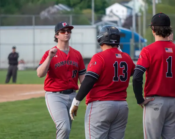 Three teammates gathered near home plate after a run