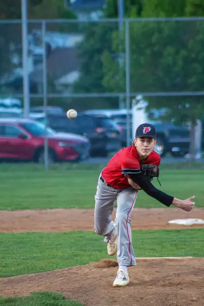 Pitcher mid-delivery with the ball on its way to the plate