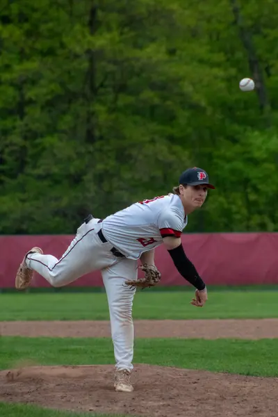 Pitcher following through on his delivery, ball in flight