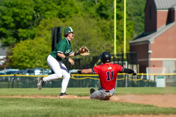 Runner sliding into second base as the fielder awaits the throw
