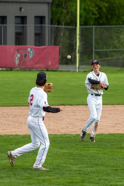 Two infielders relaying a throw across the diamond
