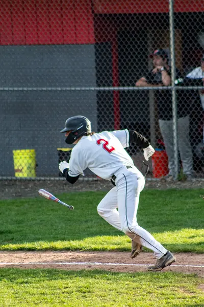 Batter following through and dropping the bat as he takes off toward first