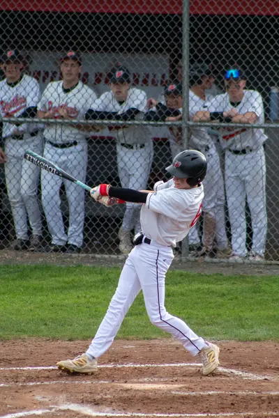 Batter following through on a swing in front of the dugout