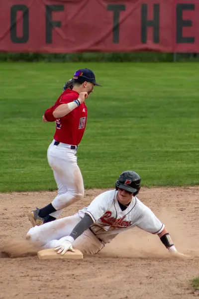 Infielder sliding to tag second base as a runner comes in