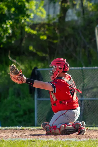 Catcher reaching out to receive a pitch