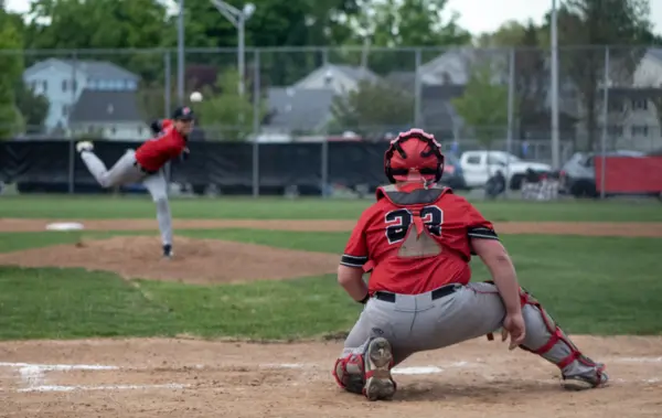 Catcher receiving a pitch as the pitcher follows through in the background