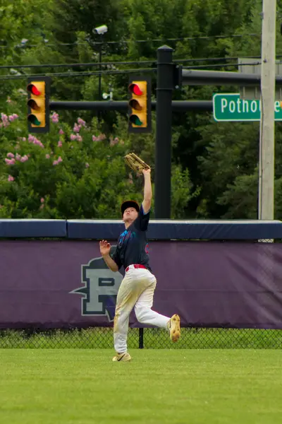 Outfielder tracking down a fly ball at the wall