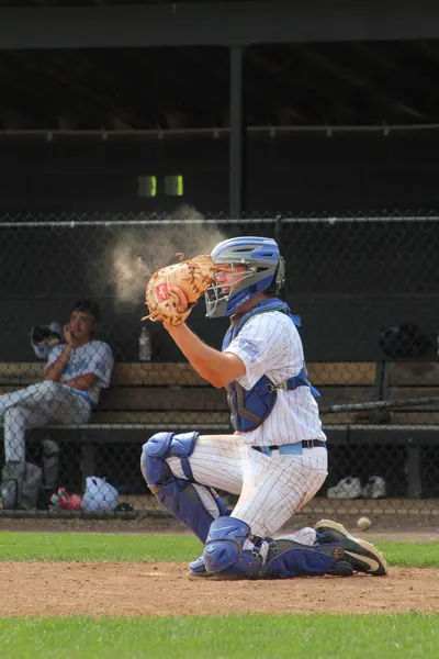 Catcher receiving a pitch, dust rising off the mitt