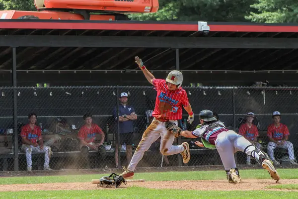 Runner leaping in as the catcher reaches for the tag