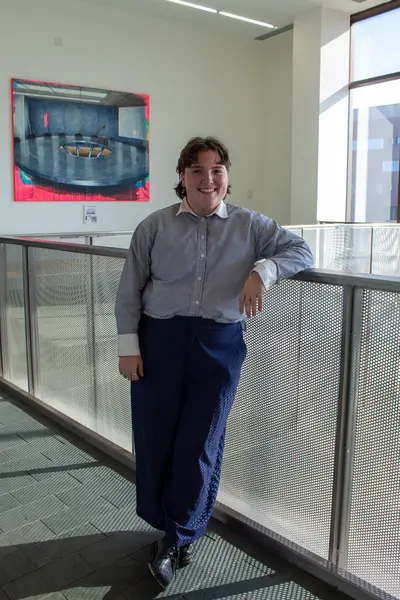 Delegate posing for a portrait next to a painting in the hallway