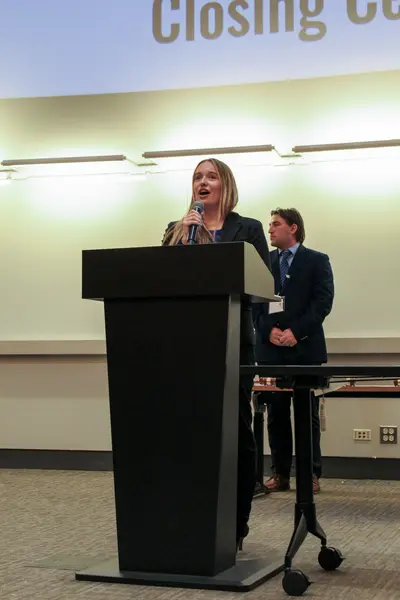 Delegate speaking into a microphone at the closing ceremony podium
