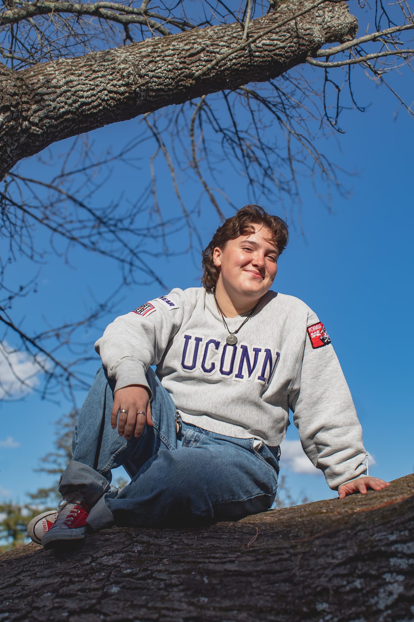 Molly senior portrait, sitting in a tree on UConn campus