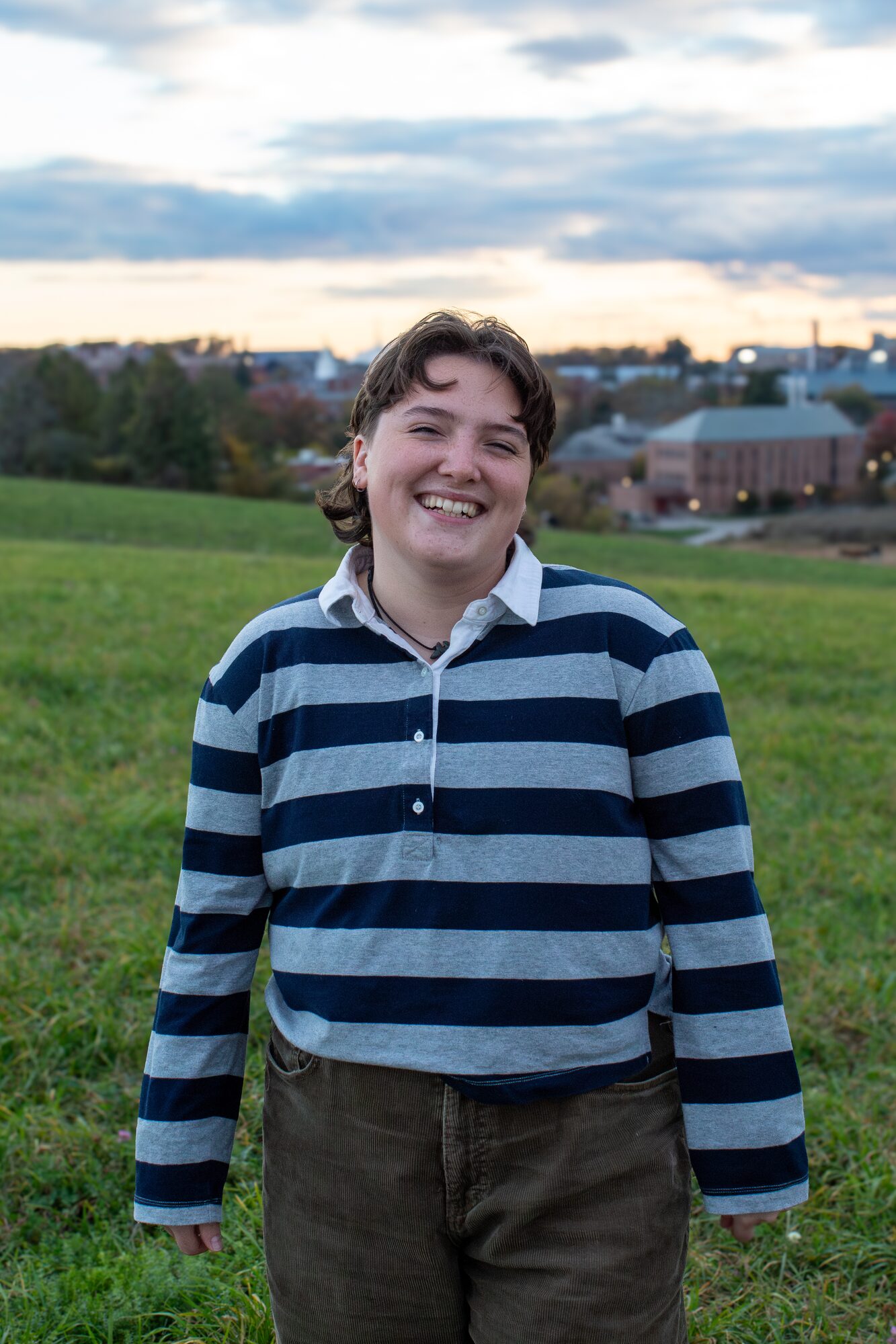 Molly senior portrait, laughing in an open field at dusk