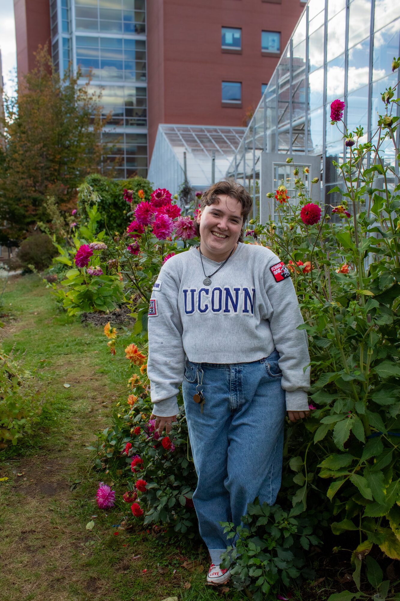 Molly senior portrait, smiling among the dahlias by the greenhouse