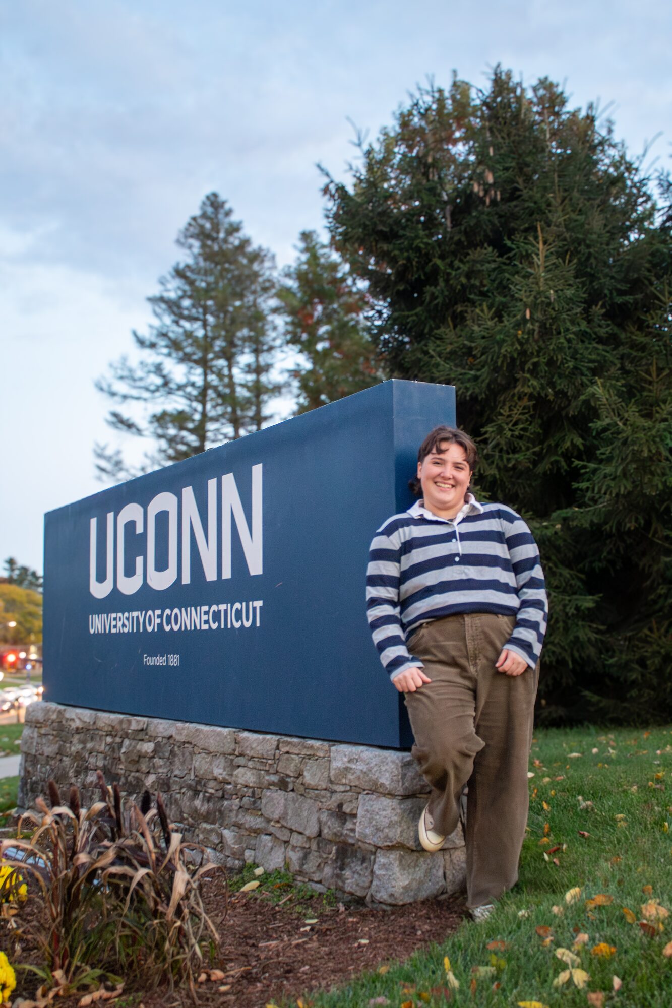 Molly senior portrait, leaning against the UConn sign